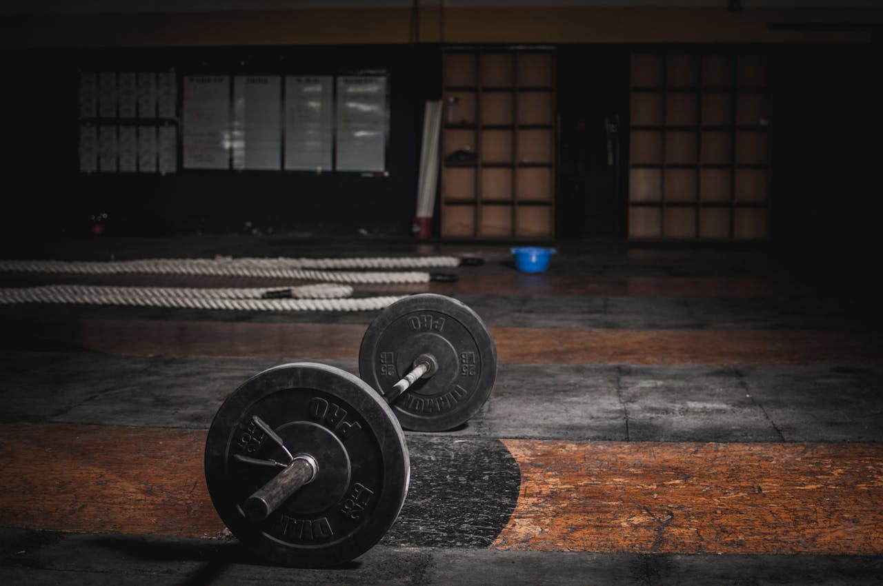 get-in-touch A lone barbell rests in an empty, dimly lit gym, emphasizing strength and solitude.