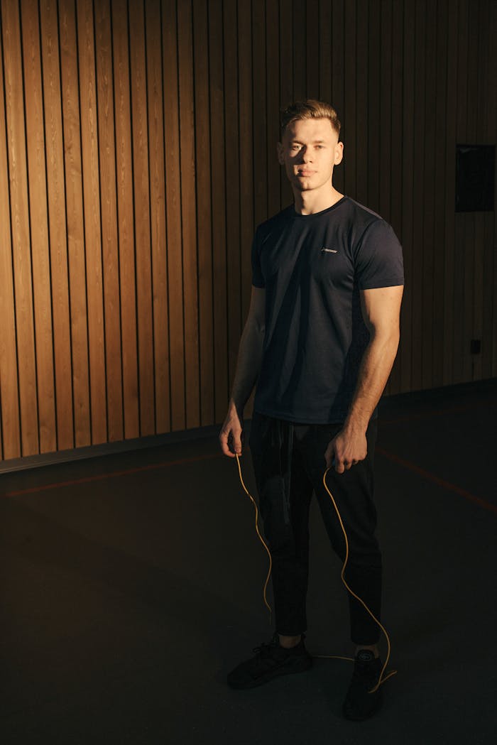 Fit young adult man with jump rope in gym, ready for workout.